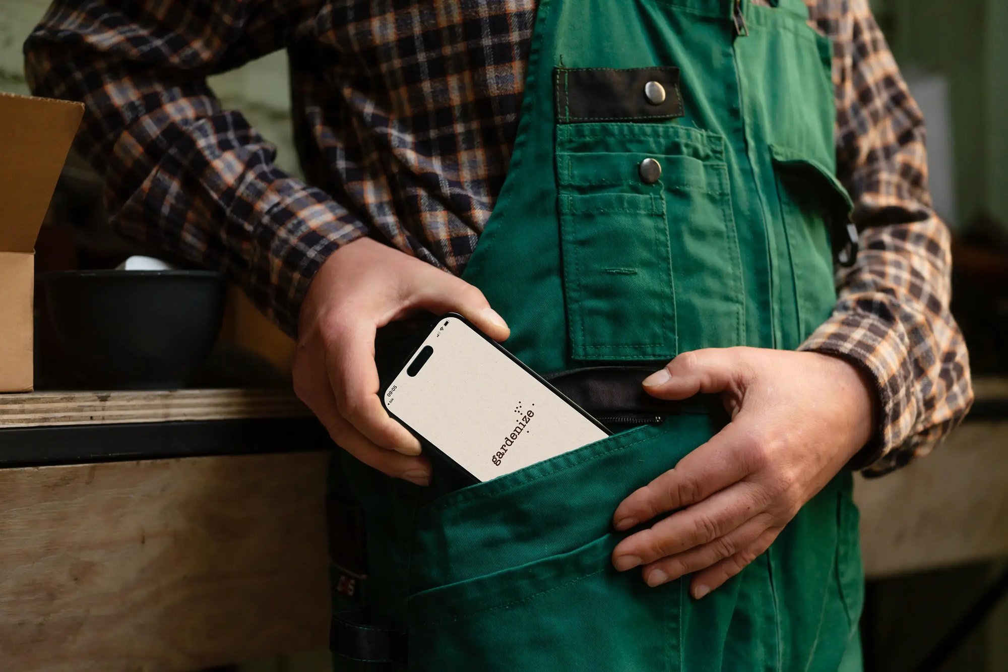 A person dressed in gardening clothes puts a smartphone with the Gardenize app in their pocket