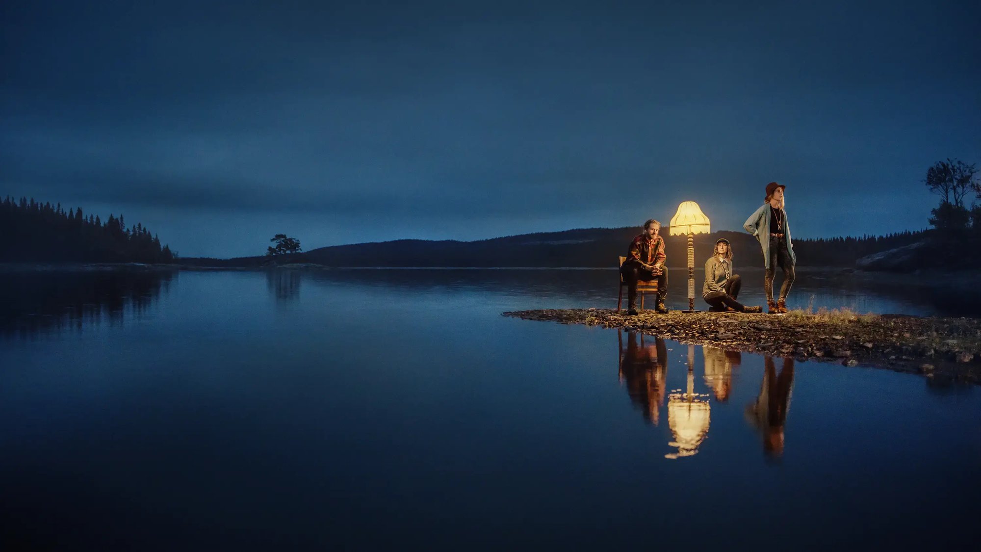 Three persons and a floor lamp standing in Jämtland's nature at dusk. Three persons and a floor lamp standing in Jämtland's nature at dusk.