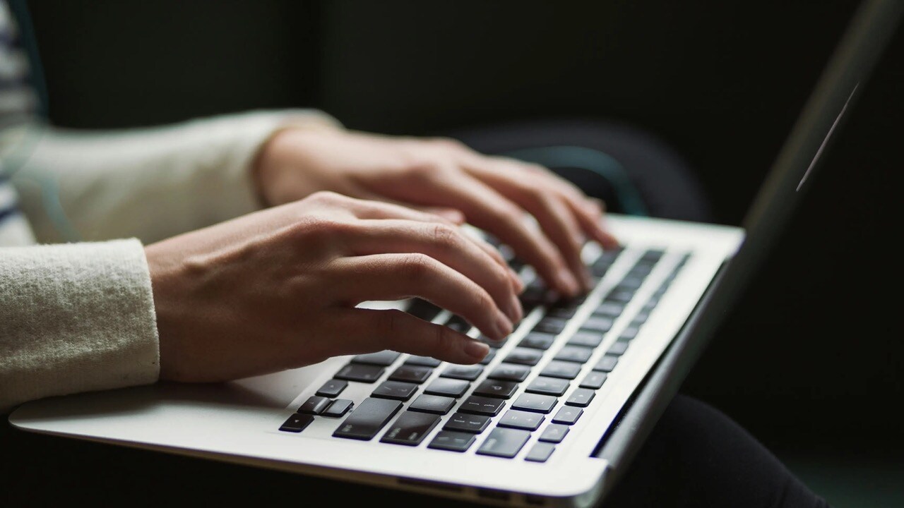 Hands typing at a laptop.