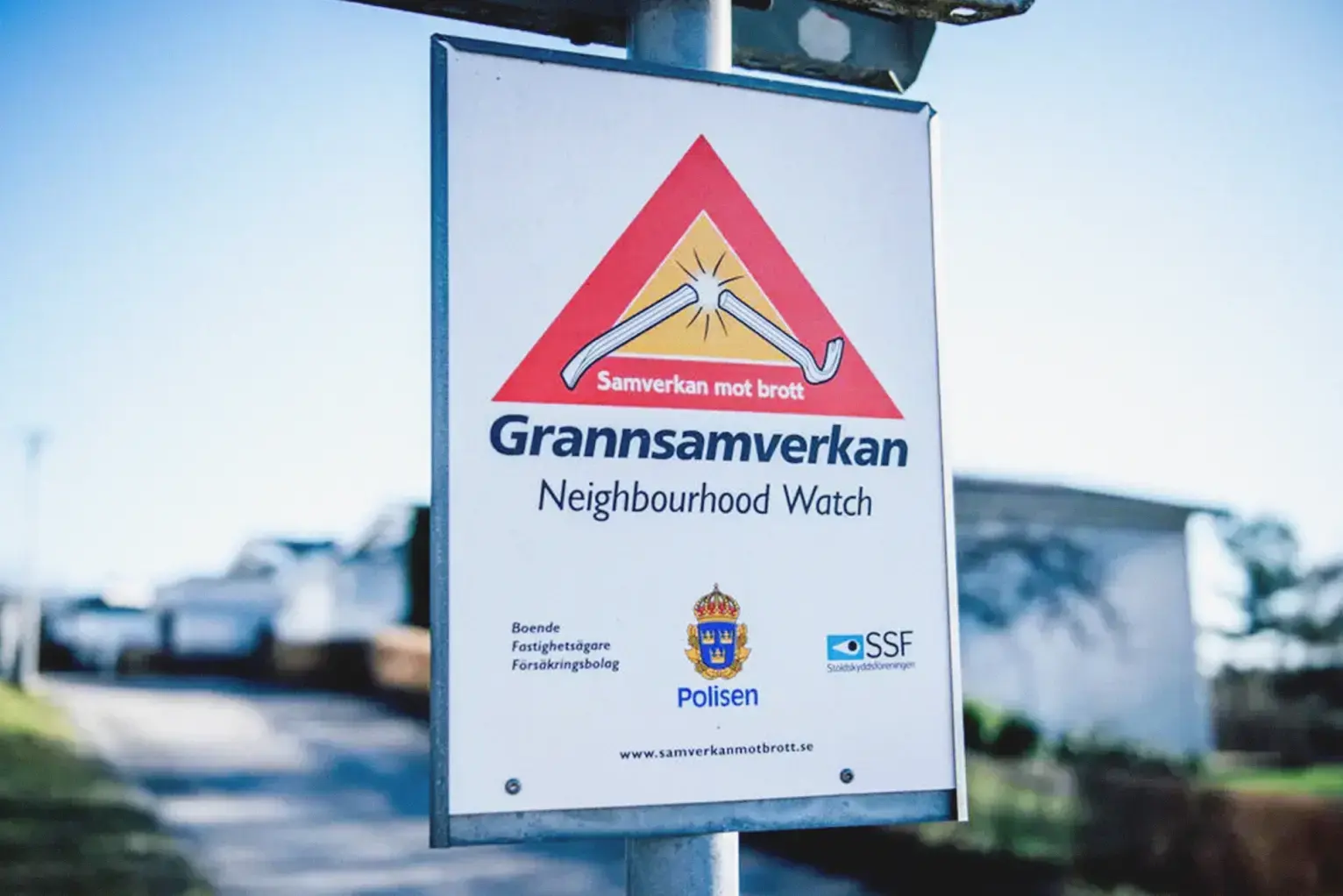 En Grannsamverkan-skylt med radhusmiljö i bakgrunden