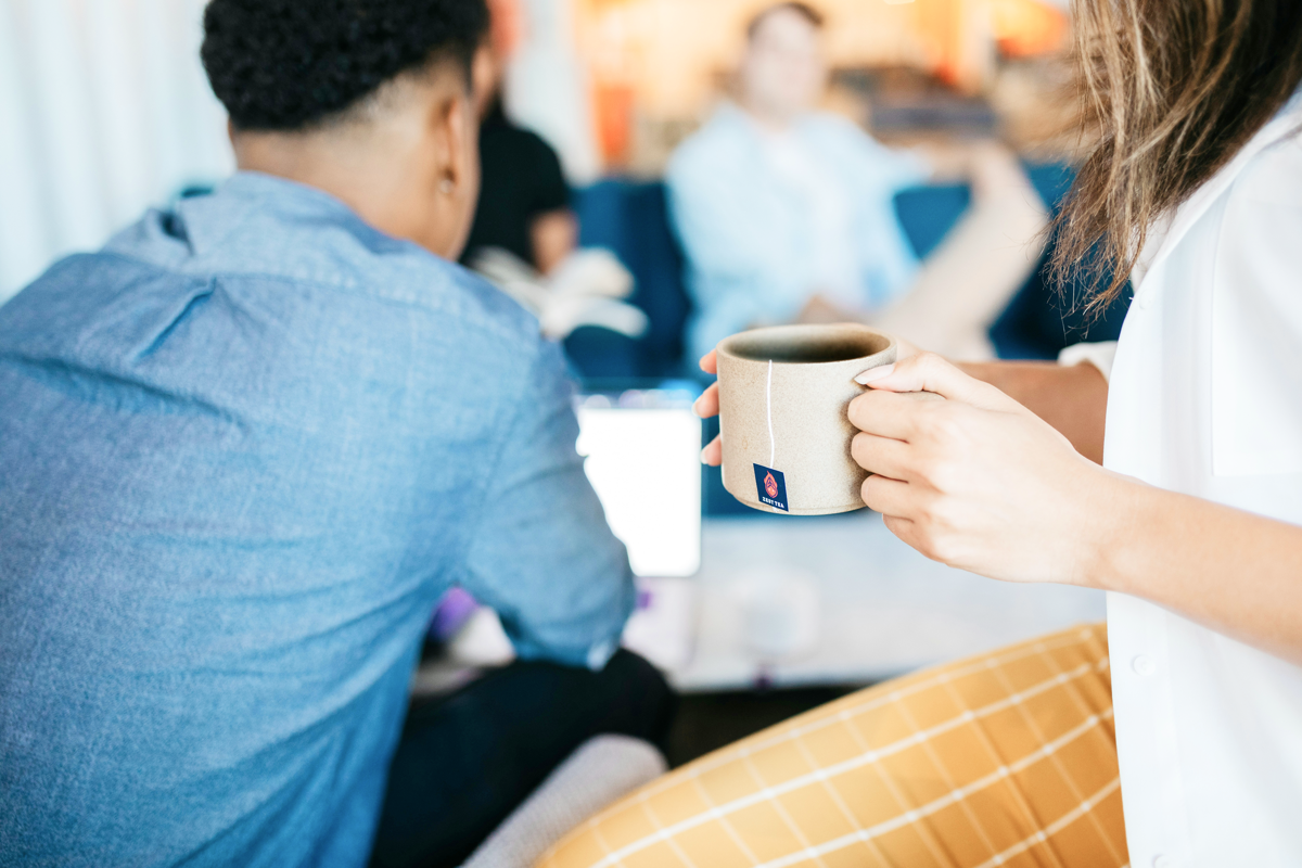 Person holding tea with others.