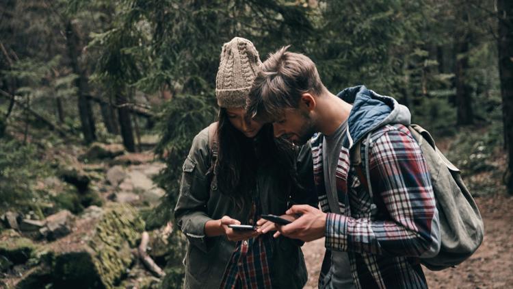 par som tittar på mobiler i skogen