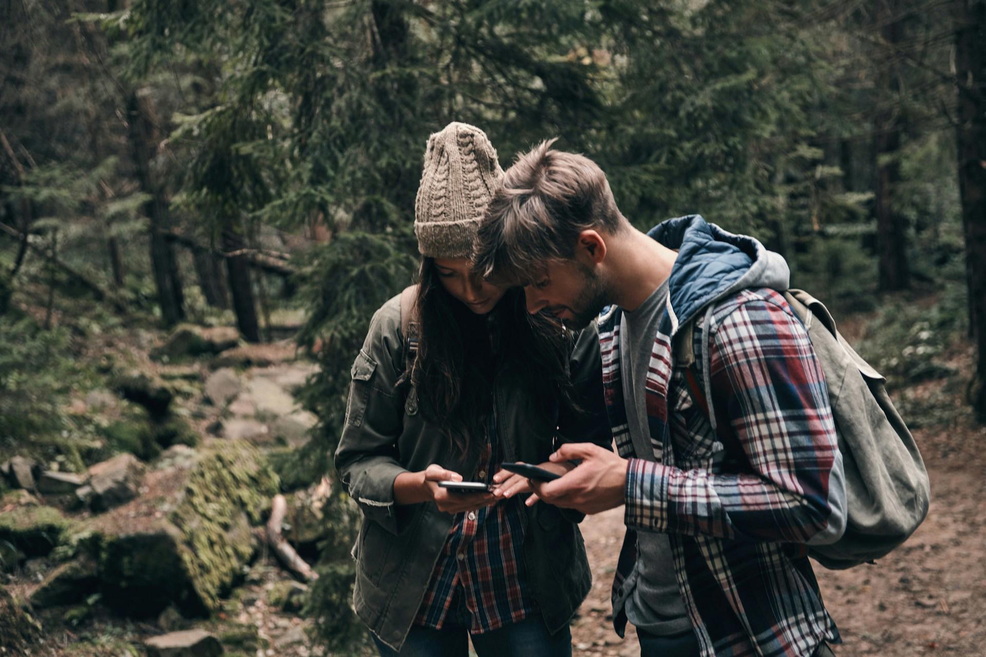 par som tittar på mobiler i skogen